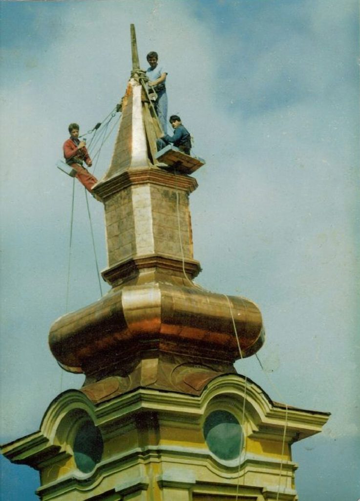 Men installing metal roof on church steeple