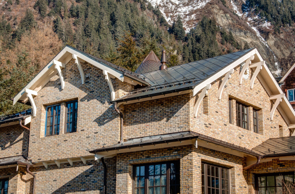 Copper snowguards on a metal roof brick home in the mountains