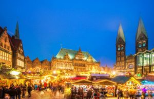 A festive scene at the Bremen Christmas Market in Germany, showcasing elegant copper roofs and spires against a backdrop of holiday lights and decorations